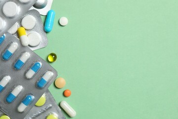 Pills in blister packs on green background, close up
