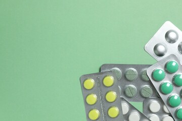 Pills in blister packs on green background, close up