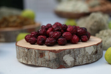 Background of a wooden coaster topped with dried cranberries, showcasing their rich red and natural texture. This is rustic composition, beauty of snacks, perfect for autumn and winter themes.