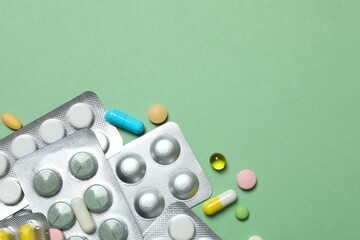 Pills in blister packs on green background, close up