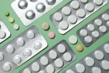 Pills in blister packs on green background, close up