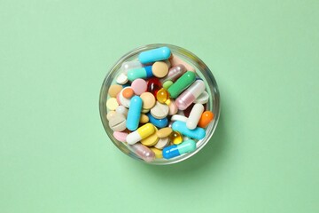 Various pills in a bowl on color background
