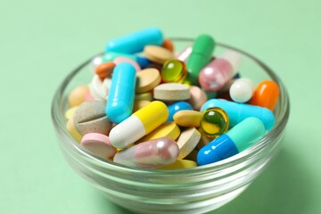 Various pills in a bowl on color background