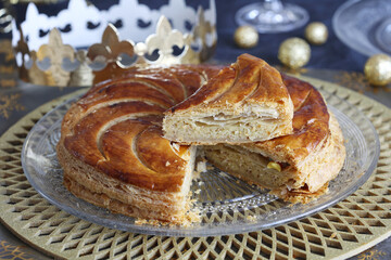 Epiphany cake. Galette des rois. Sliced french Kings cake with golden crown on the festive table.
