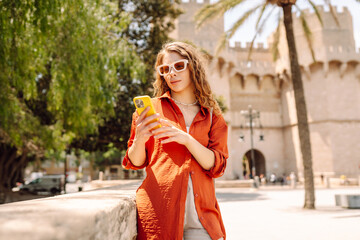 Fototapeta premium Stylish woman walking in the city with smartphone. Europe travel. Concept of blogging, technology, weekend.