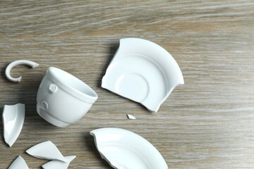 White cup and plate broken on gray background