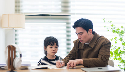 Fototapeta premium Young Asian father and daughter studying together