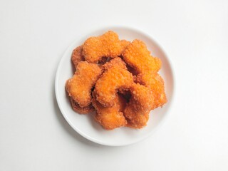 Fried chicken nuggets in a white plate on a white background. Top of view. 