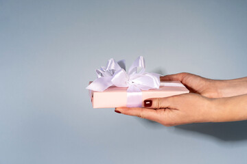 Female hands holding a gift box on a blue background. Gift for Christmas, Valentine's Day, birthday. Beautiful festive background.