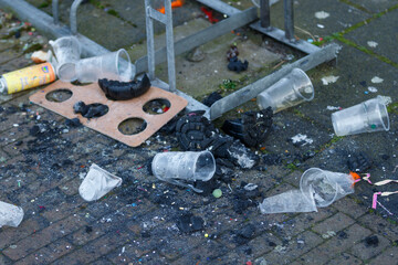 Plastic litter scattered on a city street near a waste disposal area, highlighting urban pollution challenges