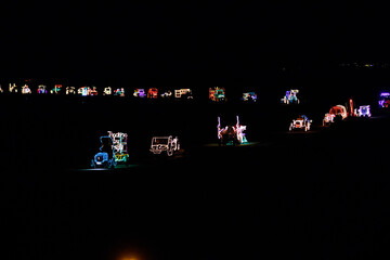 Illuminated agricultural vehicles parade through the polder countryside at night showcasing festive lights and creativity