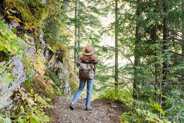 Woman with backpack hiking outdoors in the Forest. Trekking in the Pine Woods. Hiking, recreation and sports in nature.