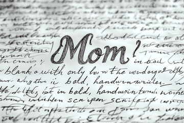 "Mom" is written in bold script amidst cursive text on paper. Concept of handwritten note or letter. For greeting card design.