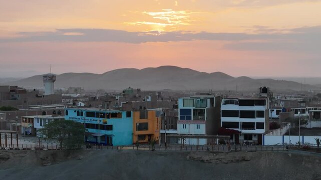 sunrise and desert mountains behind a very simple village buildings in a remote desert town located on coast of peru