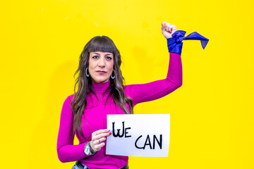 Woman showing we can sign and raising fist on yellow background