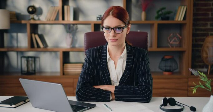 Portrait of businesswoman sitting at desk looking at camera in modern office.