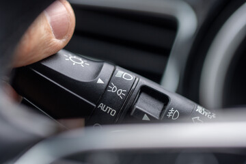 A man’s hand moves the light switch panel on a passenger car dashboard. © Robert
