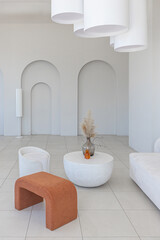 modern pure white interior design of a sprsious sitting room with soft stylish furniture. Large windows frame creating a serene atmosphere during daylight.