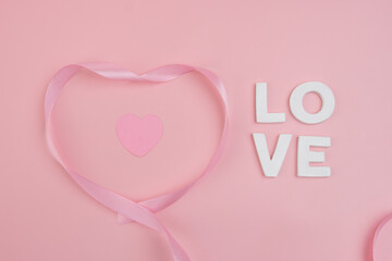 A pink ribbon forming a heart shape around a smaller pink heart with the word LOVE spelled out...