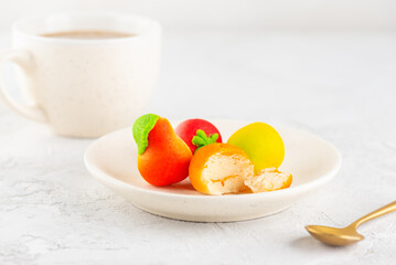 Marzipan candies in the form of fruits in a plate with a cup of coffee.