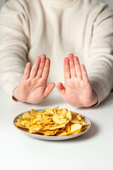 Woman pushing away plate with fried chips. No to fast food. Healthy eating concept. Rejecting junk...