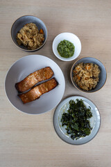 Set of dinner for two consist of rice, grilled salmon, and seaweed salad.