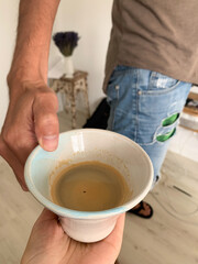 Close-up of hands holding a ceramic cup of coffee in a cozy home setting