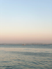 Serene seascape with a sailboat on calm waters during sunset