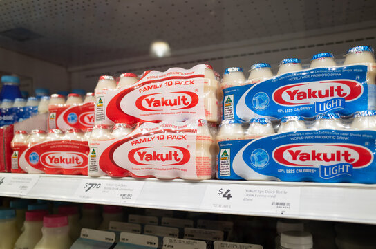 Retail shelves stocked with family-pack Yakult probiotic dairy beverages in both regular (red packaging) and light (blue packaging) varieties, displayed in an Australian supermarket.