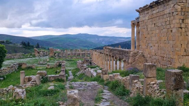 Panning shot of antique Roman ruins and the back of an ancient temple at the histroric site of Djemila Algeria on an cloudy spring afternoon