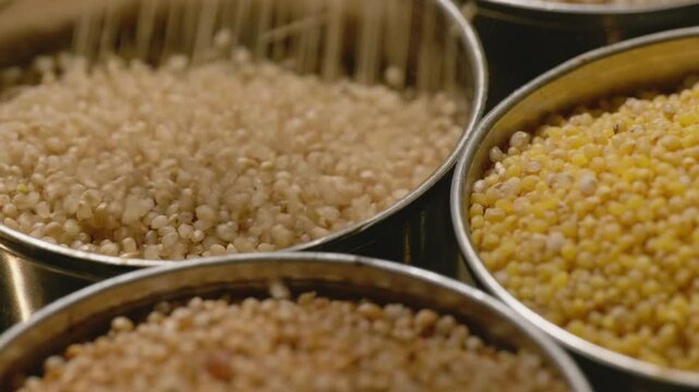 filling little millet in steel bowl with foxtail millet and barnyard millet for storage, 4k , close up, stable shot