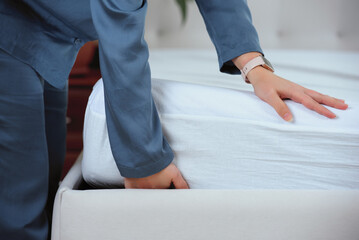 Woman's hand puts a cover on the mattress to protect it from water and house dust mites