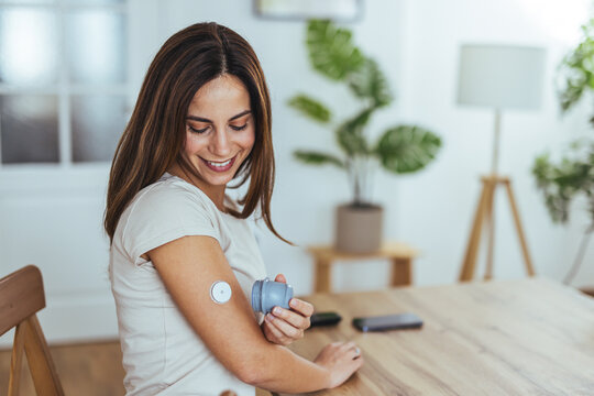 Smiling Woman Using Glucose Monitor At Home For Health Tracking