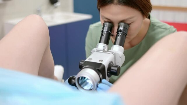 Gynecologist examines a patient using microscope in a gynecological chair. Doctor performs a colposcopy on a young girl in a modern medical office. Prevention and diagnosis of cervical cancer.