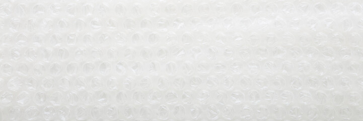 White transparent plastic air bubble film background. Closeup. Material for fragile products packaging. Wide banner. Empty place for text. Top down view.