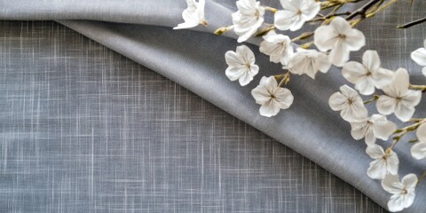 Gray and white folded napkins with artificial flowers on textured background