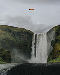 Skógafoss waterfall in South Iceland with a paraglider soaring above...