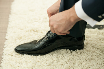 Man tying shoe laces. Close-up of man's hands tying shoe laces on black classic shoes