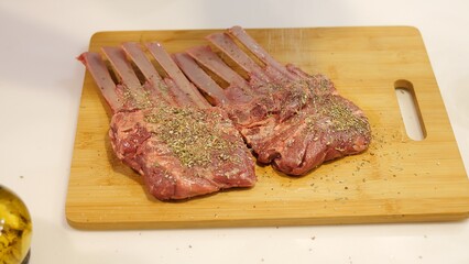 Man showcasing culinary skills by seasoning fresh ribs on wooden board Spices enhance flavor and prepare meat for grilling perfection Smoky aroma and spices bring gourmet barbecue experience