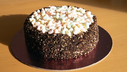 The photo shows a cake with brown edges and a light top. Marshmallows of different colors are present on top of the cake.