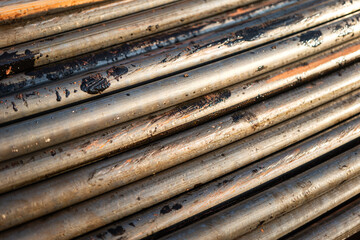 Stack of pipeline of tubing pipe in dirty condition that used in the oil production industrial. Close-up and selective at the object.