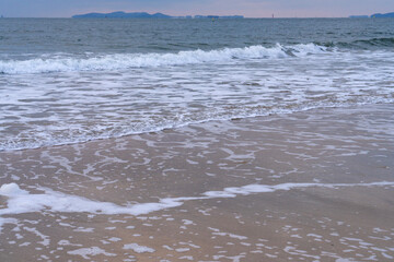 tranquil seascape with surfs on the beach during sunset
