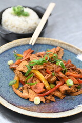 The dish features marinated pork spring onions, and rice, presented on a wooden table with a rustic plate, highlighting the rich flavors of Korean cuisine.