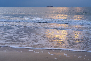 tranquil seascape with surfs on the beach during sunset
