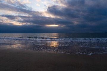 tranquil seascape with surfs on the beach during sunset