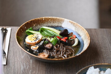 A close-up shot of a delicious bowl of ramen served on a rustic plate in a restaurant setting.