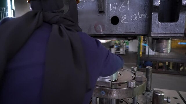 Close up view of an employee working on the hydraulic press process in a heavy industry factory.