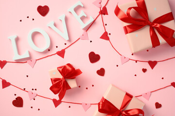Happy Valentine's Day concept. Flat lay composition with red and pink heart decorations, and gift boxes wrapped with red ribbons. The word 