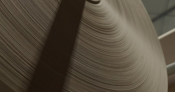 Close-up of a large industrial paper reel used in manufacturing, highlighting layered textures and production processes in a factory setting
