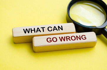 Fototapeta premium Side view of What Can Go Wrong text on wooden blocks with magnifying glass